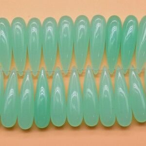 May include: A strand of light green glass beads in a teardrop shape.