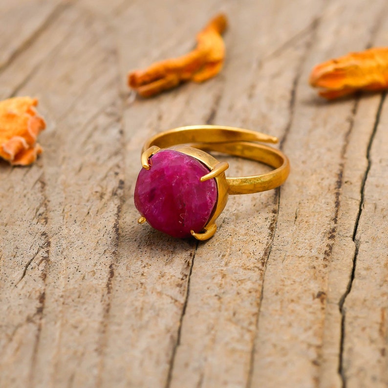 May include: A gold ring featuring a large, faceted, pink gemstone set in a claw setting.