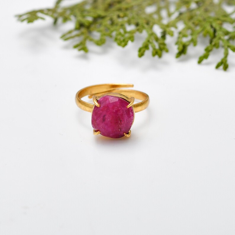 May include: A gold ring with a large, round, pink gemstone.