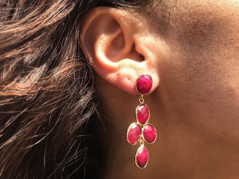 May include: Gold dangle earrings with a cluster of five red gemstone drops.