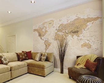 Puede incluir: Una sala de estar con un gran mural de mapa del mundo en la pared. El mapa es de estilo vintage con tonos marrones y beige. Hay un sofá seccional con cojines marrones y un sillón marrón con una manta.