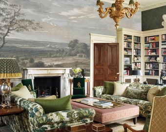 Puede incluir: Una sala de estar con un gran mural de paisaje en la pared, una chimenea, una librería y varios sofás y sillas con estampado floral y verde.