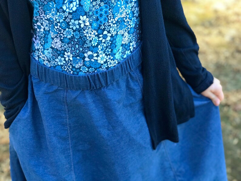 May include: A blue denim skirt with an elastic waistband. The skirt is long and flowing, and it is paired with a floral print top.
