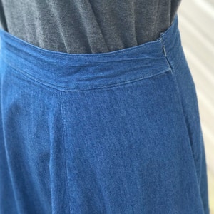 May include: A denim skirt with a dark blue wash and a waistband. The skirt is a-line and has a slight flare at the bottom.