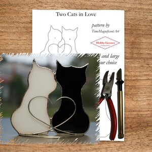 May include: Two black and white stained glass cats with a heart between them. The cats are facing each other and are in a loving embrace. The stained glass is set on a metal stand. The image also includes a pattern for the stained glass cats, a pair of pliers, and a glass cutter.