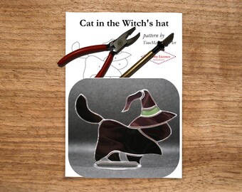 May include: A stained glass cat wearing a witch's hat, with a pattern and tools. The cat is black with a purple hat and green trim. The tools include red-handled pliers and a brass-colored tool. The text reads "Cat in the Witch's hat".