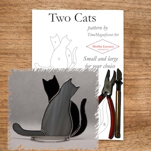 May include: A stained glass pattern of two cats, one sitting and one standing, with numbered sections for assembly. The pattern is printed on white paper with the title "Two Cats" and the text "pattern by TimeMagnificentArt" and "Hobby Licence". The text "Small and large for your choice" is also printed on the paper. Two tools, a pair of pliers and a soldering iron, are shown on the right side of the paper.