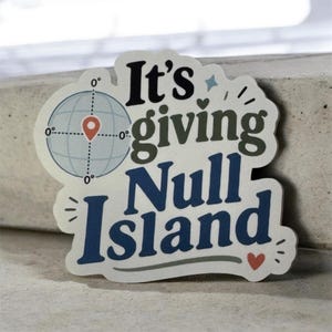 May include: A die-cut sticker featuring a light blue globe icon with a red location pin at the center. The text reads It's giving Null Island in black, dark green, and dark blue lettering, accented with a small red heart and decorative lines.