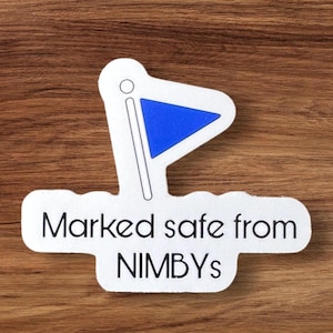 May include: White sticker with a blue flag and the text "Marked safe from NIMBYs".