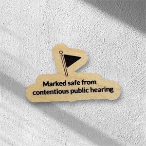 May include: Wooden sign with a black flag icon and the text "Marked safe from contentious public hearing."