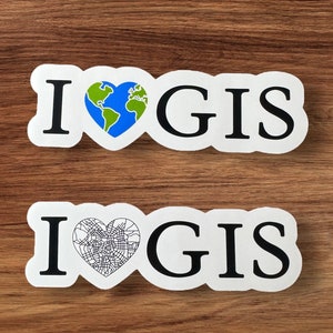 May include: Two white stickers with black text that reads "I love GIS". The first sticker features a green and blue globe inside a heart. The second sticker features a black and white city map inside a heart.