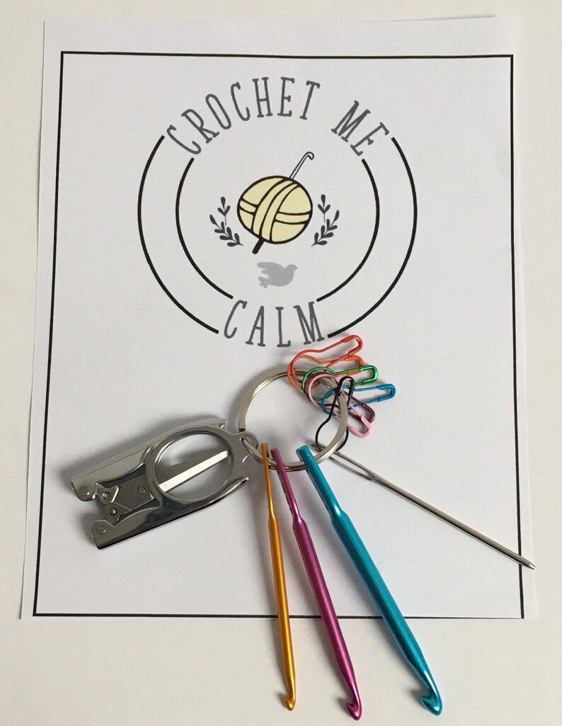 May include: A set of crochet hooks, a pair of scissors, and a set of colorful stitch markers. The set is packaged with a white card with the text "Crochet Me Calm".