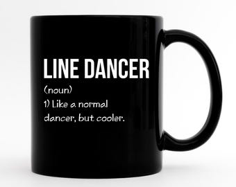 Może przedstawiać: Czarny ceramiczny kubek z białym napisem "LINE DANCER", a następnie definicją. Definicja brzmi: "(rzeczownik) 1) Jak normalny tancerz, ale fajniejszy."
