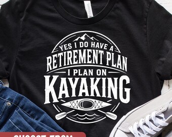 以下が含まれることがあります： 「YES I DO HAVE A RETIREMENT PLAN - I PLAN ON KAYAKING」と書かれた白いグラフィックが特徴の黒いTシャツ。カヤック、パドル、山のイメージが含まれています。このシャツは10色、XS-5XLサイズで利用可能です。