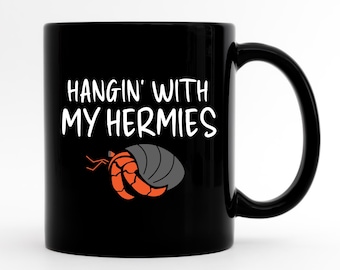 May include: Black coffee mug with white text that reads "Hangin' with my Hermies" and a cartoon hermit crab illustration.