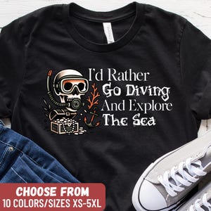 May include: Black t-shirt featuring a scuba diving skull graphic and the text "I'd Rather Go Diving And Explore The Sea." The shirt also has the text "CHOOSE FROM 10 COLORS/SIZES XS-5XL."