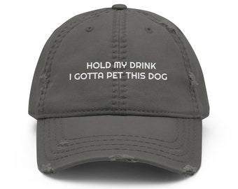 May include: A gray distressed baseball cap with the text "Hold my drink I gotta pet this dog" embroidered in white.