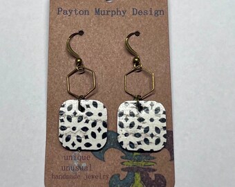 May include: A pair of black and white patterned square earrings with gold hexagon hoops. The earrings are on a brown card with the text "Payton Murphy Design", "unique", "unusual", and "handmade jewelry".