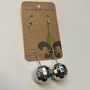 May include: Silver-toned chain earrings with faceted, mirrored disco ball pendants. The earrings hang from silver hooks and are displayed on a brown card with the text "Payton Murphy Design" and "unique unusual handmade jewelry".