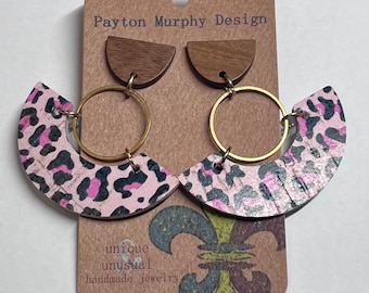 May include: A pair of pink and black leopard print wood earrings with gold hoops. The earrings are handmade and feature the text "Payton Murphy Design" and "unique unusual handmade jewelry".
