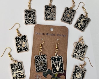 May include: Gold tone earrings with black card-shaped charms featuring tarot card imagery. The cards include The Lovers, The Magician, The Chariot, The World, The Tower, The Star, The Sun, The Moon, The Strength, Death, and Judgement. The earrings are handmade and unique.