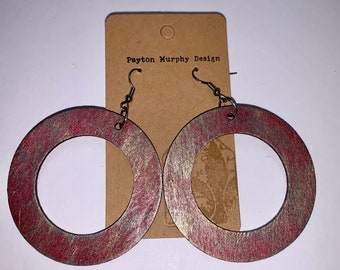 Puede incluir: Pendientes grandes y circulares de madera con acabado metálico rojo y dorado. Los pendientes están sujetos a una etiqueta marrón que dice "Payton Murphy Design". Los pendientes tienen cierre de gancho.
