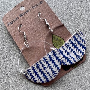 Puede incluir: Un par de pendientes con estampado azul y blanco, con aro transparente y gancho plateado. Los pendientes están hechos por Payton Murphy Design.