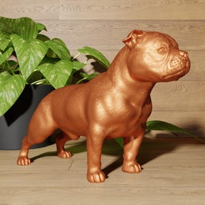 Könnte beinhalten: Eine kupferfarbene Statue eines Staffordshire Bullterriers, die auf einer Holzoberfläche steht.