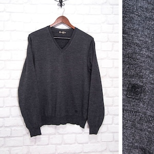 Puede incluir: Un suéter gris oscuro de cuello en V y mangas largas. El suéter está hecho de un material suave y cómodo y tiene una textura sutil. El suéter tiene un pequeño logotipo en el lado izquierdo del pecho.