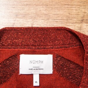 May include: Red sparkly sweater with a white tag that says "N&Uuml;MPH" and "MAKE AN ENTRANCE" with a size XL label.