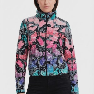 May include: A black zip-up jacket featuring a vibrant, all-over butterfly print in shades of pink, purple, blue, and teal. The jacket has a high collar, long sleeves, and a quilted texture, paired with solid black pants.