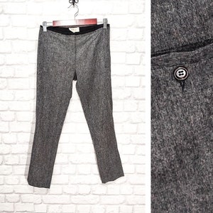 May include: Gray slim-fitting pants with a button closure. The pants have a subtle herringbone pattern.