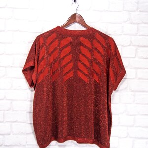 May include: Red sparkly short-sleeved sweater with a geometric pattern.