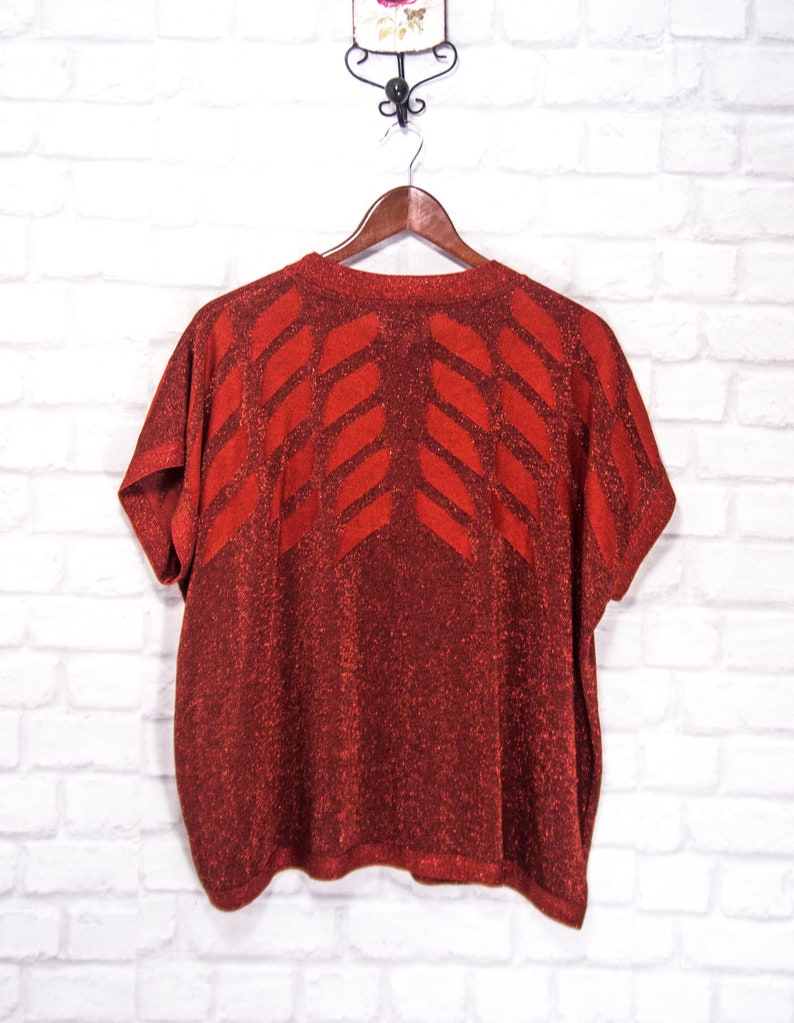 May include: Red sparkly short-sleeved sweater with a geometric pattern.