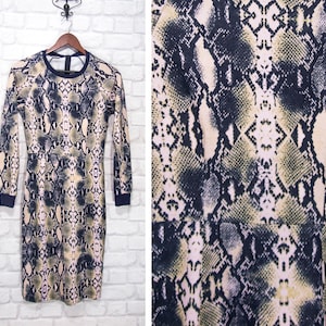 Może przedstawiać: Długa sukienka z nadrukiem wężowej skóry w odcieniach czerni, bieli i beżu. Sukienka ma dopasowany krój i okrągły dekolt.