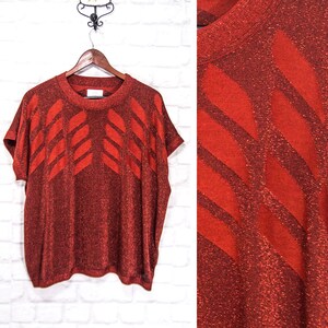May include: A red sparkly knit top with a geometric pattern of diagonal lines. The top has short sleeves and a round neckline.