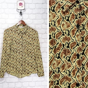 Puede incluir: Una camisa de manga larga con botones y estampado de piel de serpiente marrón y amarillo.