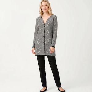 May include: A long-sleeved black and white geometric patterned cardigan with a V-neck and black buttons. The cardigan is paired with black pants and black flats. The outfit is suitable for a variety of occasions.