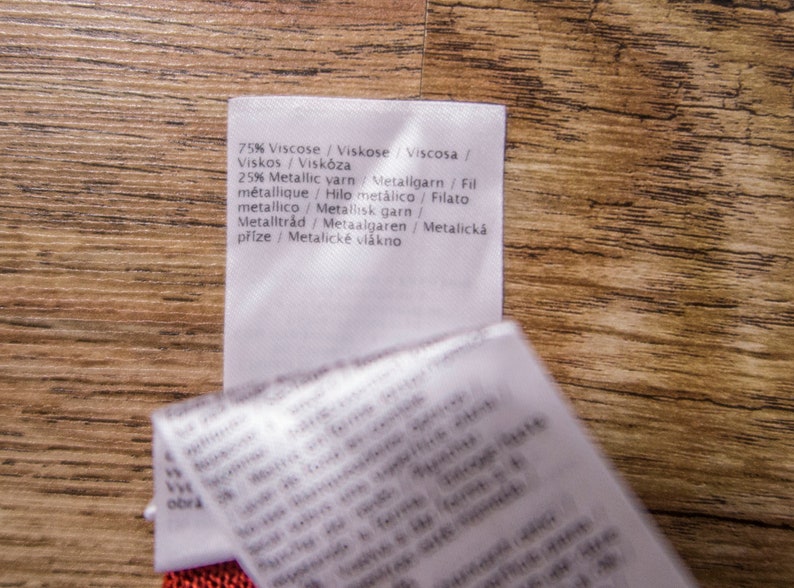 May include: A white fabric label with the text "75% Viscose/Viskose Viscosa/Viskos / Visk&oacute;za 25% Metallic yarn Metallgarn / Fil m&eacute;tallique/Hilo met&aacute;lico / Filato metallico/Metallisk garn/Metalltr&aring;d / Metaalgaren / Metalick&aacute; př&iacute;ze/Metalick&eacute; vl&aacute;kno" printed on it.