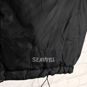 May include: Black jacket with a drawstring hem. The jacket features a small rectangular patch with the text "SEAWELL" and a star graphic. The fabric appears to be a lightweight, possibly water-resistant material.