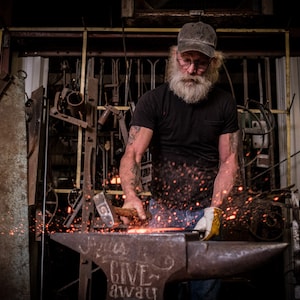 A blacksmith hammering metal at an anvil.