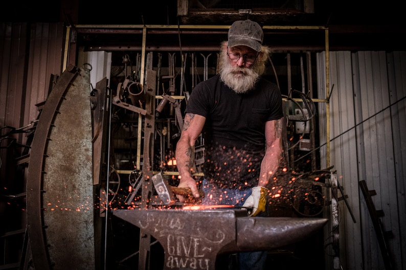 A blacksmith hammering metal at an anvil.