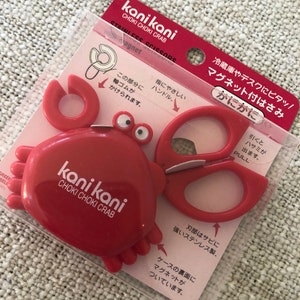 以下が含まれることがあります： カニの形をした赤いハサミセットで、カニの体に「kani kani CHOKI CHOKI CRAB」の文字が入っています。ハサミはステンレス製で、マグネットが付いています。パッケージには日本語のテキストが含まれています。