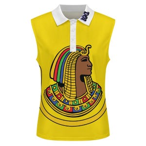 Peut inclure: Polo sans manches jaune avec un col blanc et une patte de boutonnage à trois boutons. Le t-shirt présente un motif coloré de pharaon égyptien. Le mot "DOI" est imprimé sur le col. Le motif du pharaon comprend une coiffe dorée et des accents colorés.