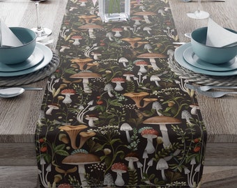 May include: A dark brown table runner with a repeating pattern of mushrooms and greenery. The mushrooms are in various shades of red, brown, and yellow. The runner is on a wooden table with place settings.