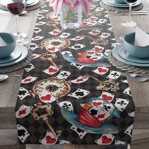 May include: A decorative table runner with a repeating pattern of playing cards, antique keys, and pocket watches. The design includes a Mad Hatter hat with playing cards. The colour scheme includes black, white, red, and gold.