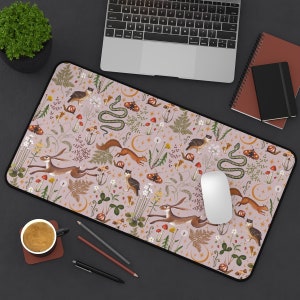 May include: A pink and beige mouse pad with a whimsical woodland design. The design features a variety of animals, plants, and insects, including a snake, a rabbit, a squirrel, and a bird. The mouse pad is perfect for adding a touch of nature to your workspace.