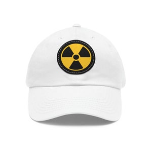 May include: White baseball cap with a yellow and black radiation symbol patch.