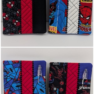 May include: Four rectangular fabric notebook covers featuring Spider-Man comic book prints in red, blue, black, and white. Each cover includes a quilted red section, a black trim with pom-pom detailing, and a side pocket containing a clear plastic pen.