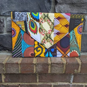 May include: A colorful patchwork fabric clutch bag with a variety of geometric and floral patterns in shades of yellow, blue, green, red, and black.
